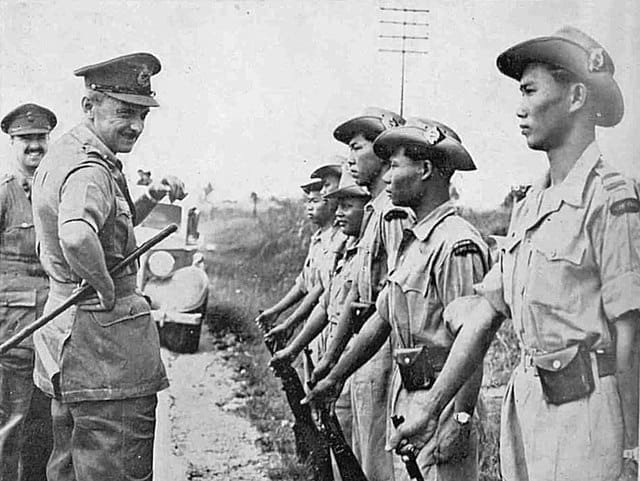 Black-and-white 1952 photograph showing Sir Gerald Templer and Major Lord Wynford inspecting uniformed members of the Kinta Valley Home Guard in Perak, Malaya, during the Malayan Emergency. Templer and Wynford stand facing a line of local guards armed with rifles along a rural roadside.