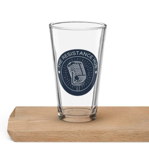 Clear pint glass with navy Resistance Hub microphone logo placed on wood block