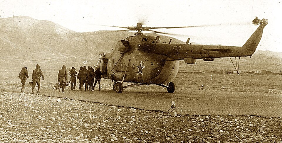Soviet Mi-8 helicopter on a landing strip with soldiers disembarking during the Soviet-Afghan War.