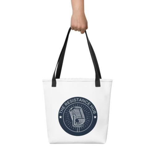 Hand holding white Resistance Hub tote bag with navy circular logo and microphone emblem