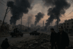 Men walk through a heavily damaged urban street as black smoke rises from multiple fires in the distance; utility poles, rubble, and armed vehicles line the road under a dark sky.