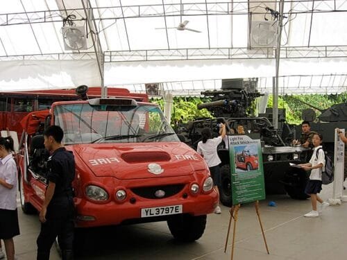 A Singapore Civil Defence Force (SCDF) Red Rhino light fire attack vehicle on public display at the Singapore Discovery Centre, with students observing the exhibit.