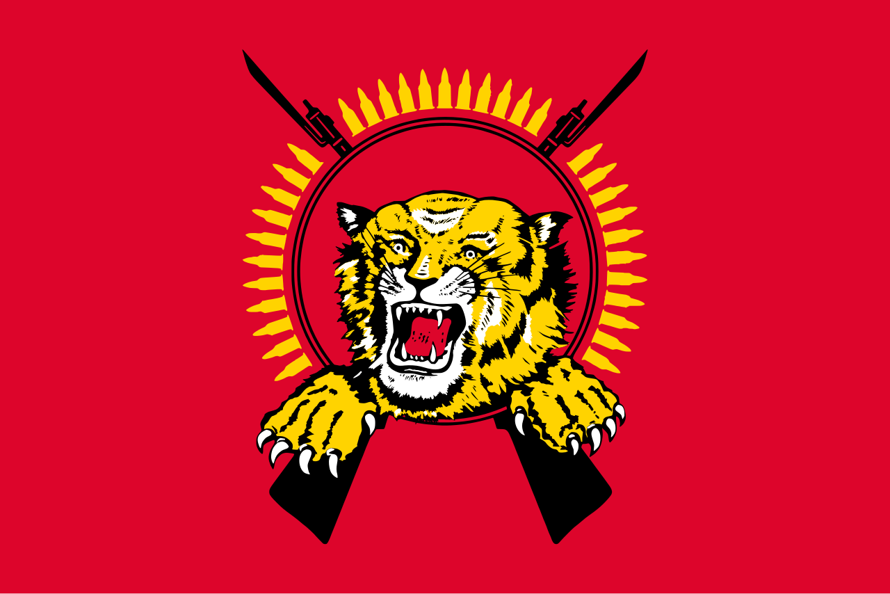 Emblem of the Liberation Tigers of Tamil Eelam: a roaring tiger head and clawed forepaws bursting through a ring of upright rifle rounds, flanked by two crossed bayoneted rifles, the insignia the Tamil Tigers flew over their parallel state in northern Sri Lanka